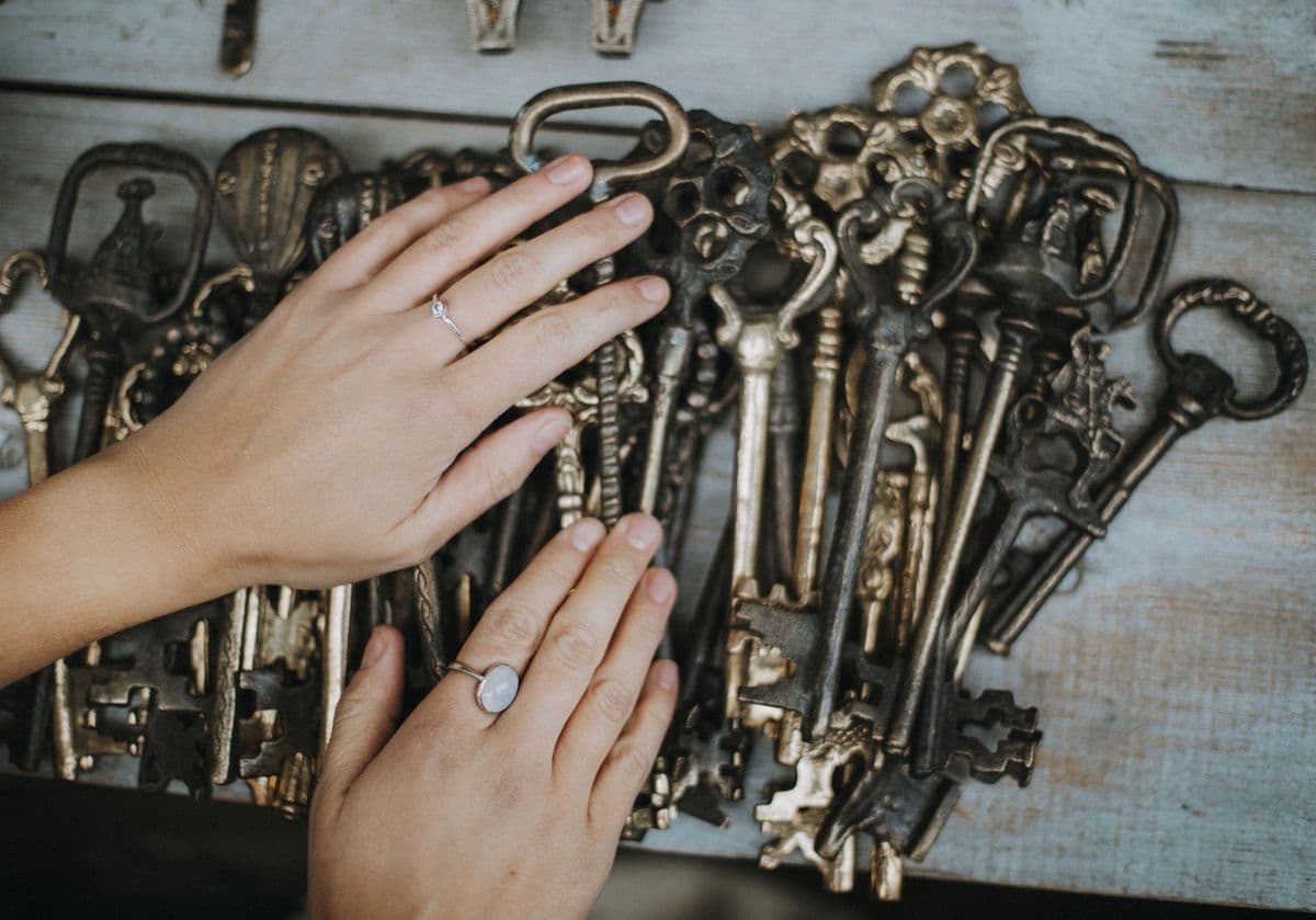hands holding a large ring of assorted vintage skeleton keys